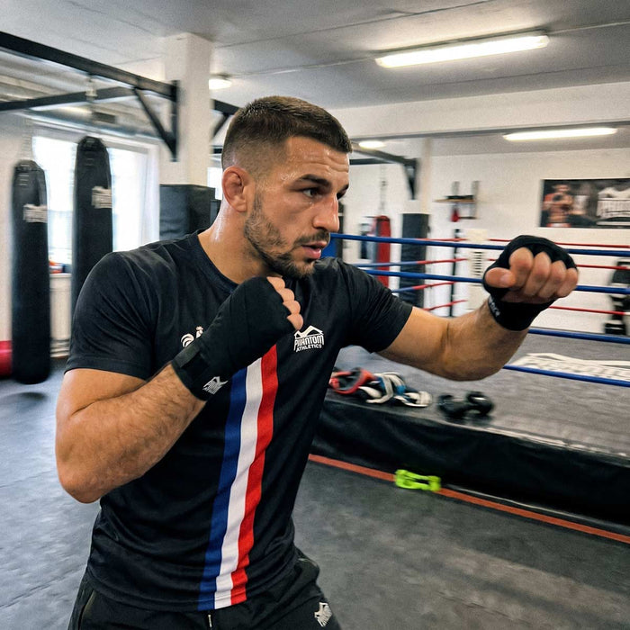Boxer mit Phantom Athletics  Trainingsshirt und Fight Shorts Team France sowie mit Boxbandagen im Gym beim Schattenboxen