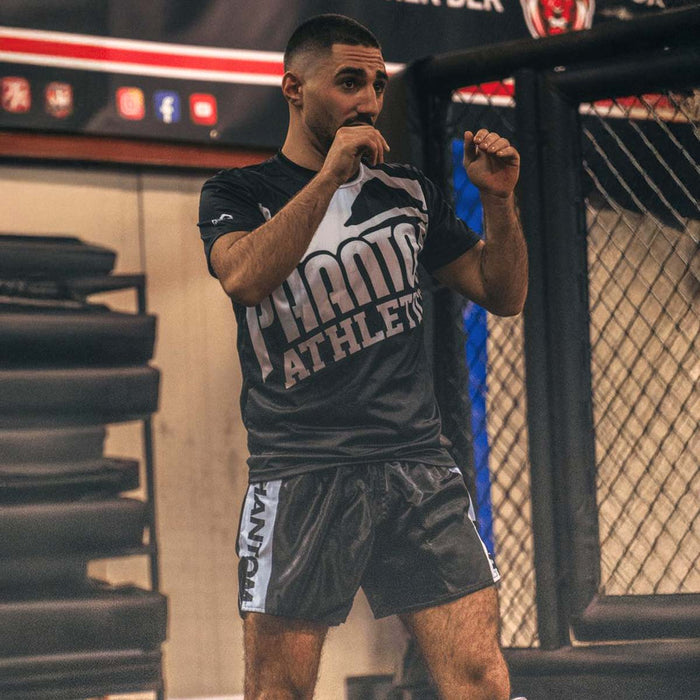 Muay Thai-Fighter Ali Atoui mit Phantom Athletics T-Shirt und Training Shorts im Gym beim Aufwärmen