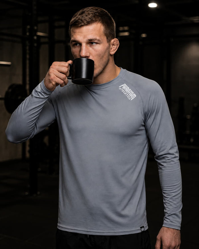 Kampfsport-Athlet mit Phantom Athletics Trainingsshirt Tactic, Fight Shorts und einer Tasse Kaffee im Gym