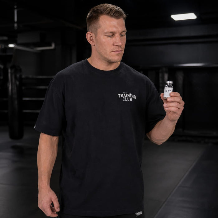 Kampfsport-Athlet mit Phantom Athletics Oversize Trainingsshirt, der gerade das Peptid LL-37 in der Hand hält