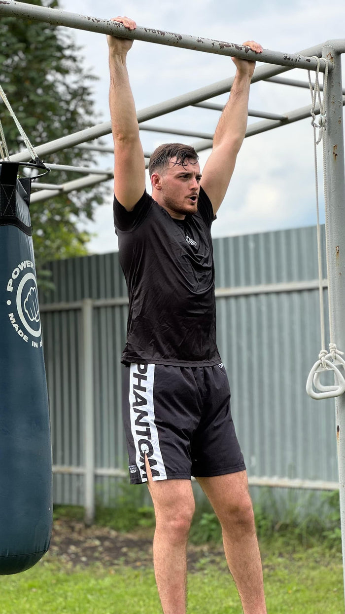 MMA-Fighter Gianni Massafra mit Phantom Athletics T-Shirt und Training Shorts beim Stretching