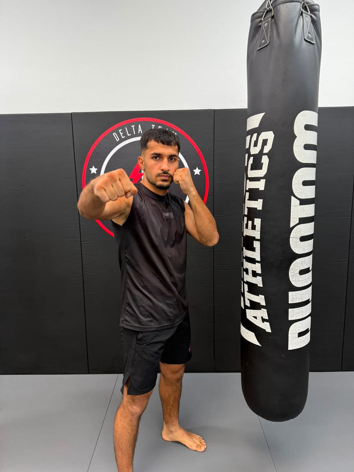 Kickboxer Abdullah Zulmai mit Phantom Athletics Tanktop, Fight Shorts und Boxsack im Gym