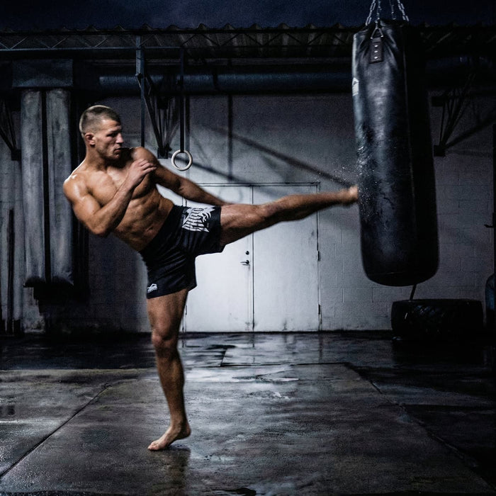 Kampfsport-Athlet mit Phantom Athletics Fightshorts und Boxsack im Training