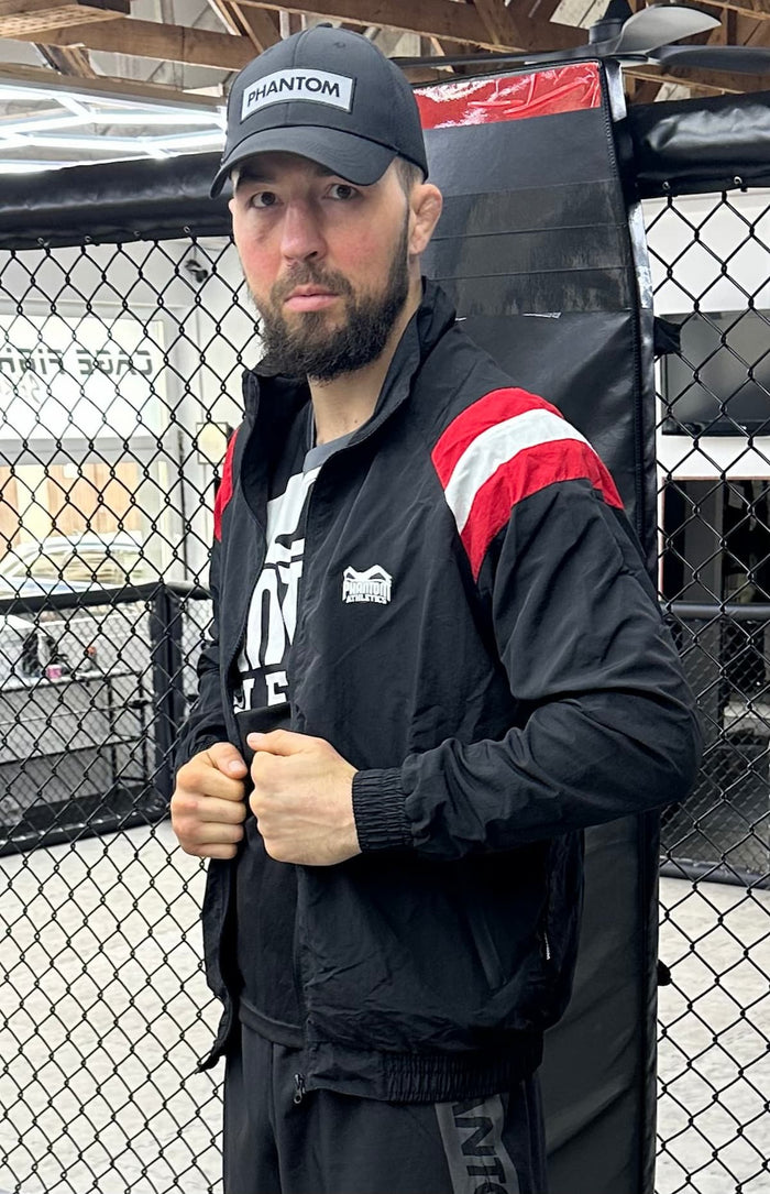 MMA-Fighter Daniel Schordje mit Phantom Athletics Tanktop, Fight Shorts, Trainingsjacke und Kappe im Gym