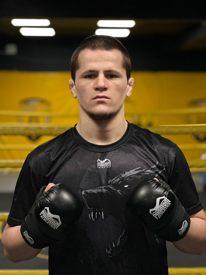 MMA-Fighter Suhrob Ikromov mit Phantom Athletics Rashguard und MMA-Handschuhen im Gym