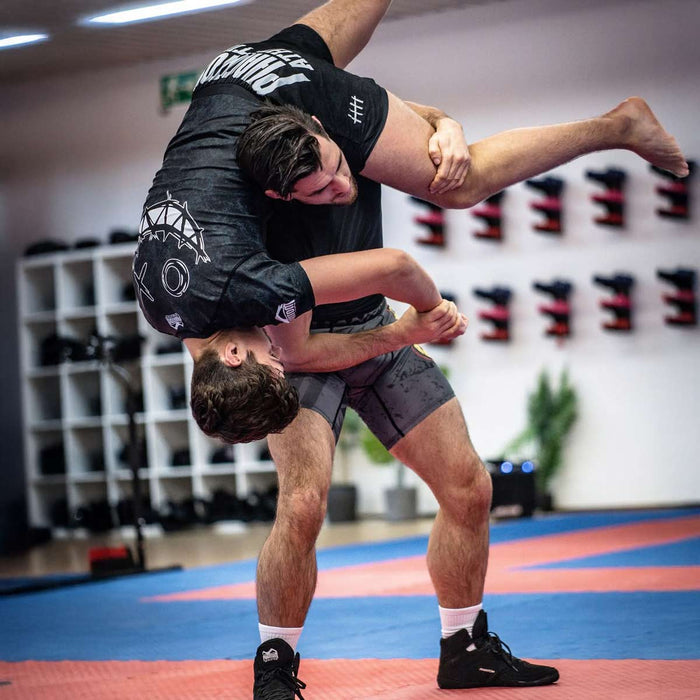 MMA-Fighter Nikolaos Serbezis mit Phantom Athletics Rashguard, Fight Shorts und Ringerschuhen während einem Takedown im Training