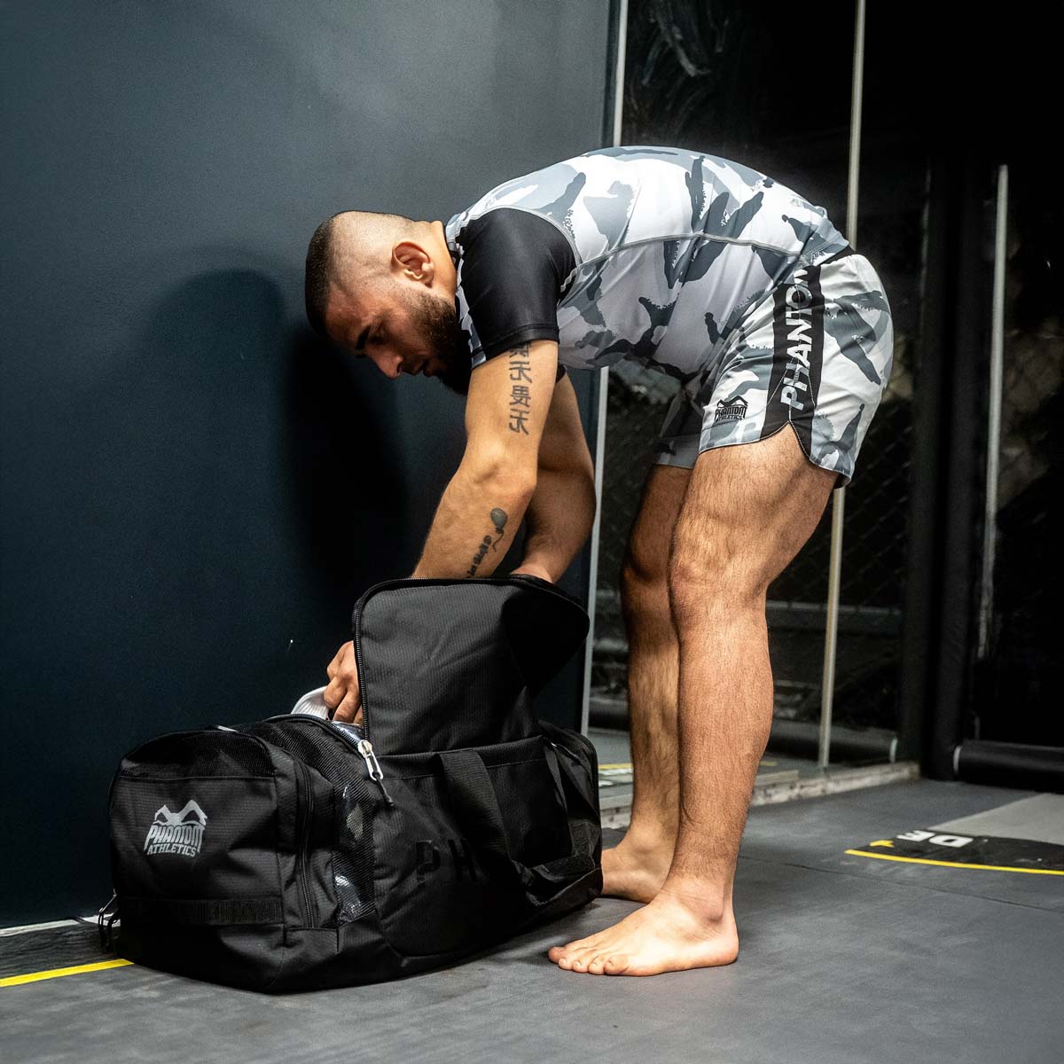 MMA-Fighter Mohammed Walid mit Phantom Athletics Rashguard und Fightshorts im Gym mit gepackter Phantom Trainingstasche