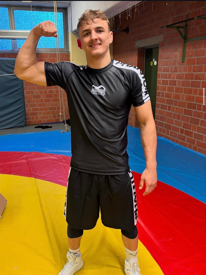 Ringer Radu Placinta mit Phantom Athletics Rashguard, Tights, Fight Shorts und Ringerschuhen auf der Matte