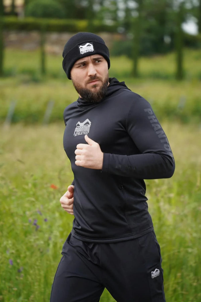 Ringer Ahmed Dudarov mit Phantom Athletics Hoodie, Jogginghose und Mütze beim Laufen Outdoor