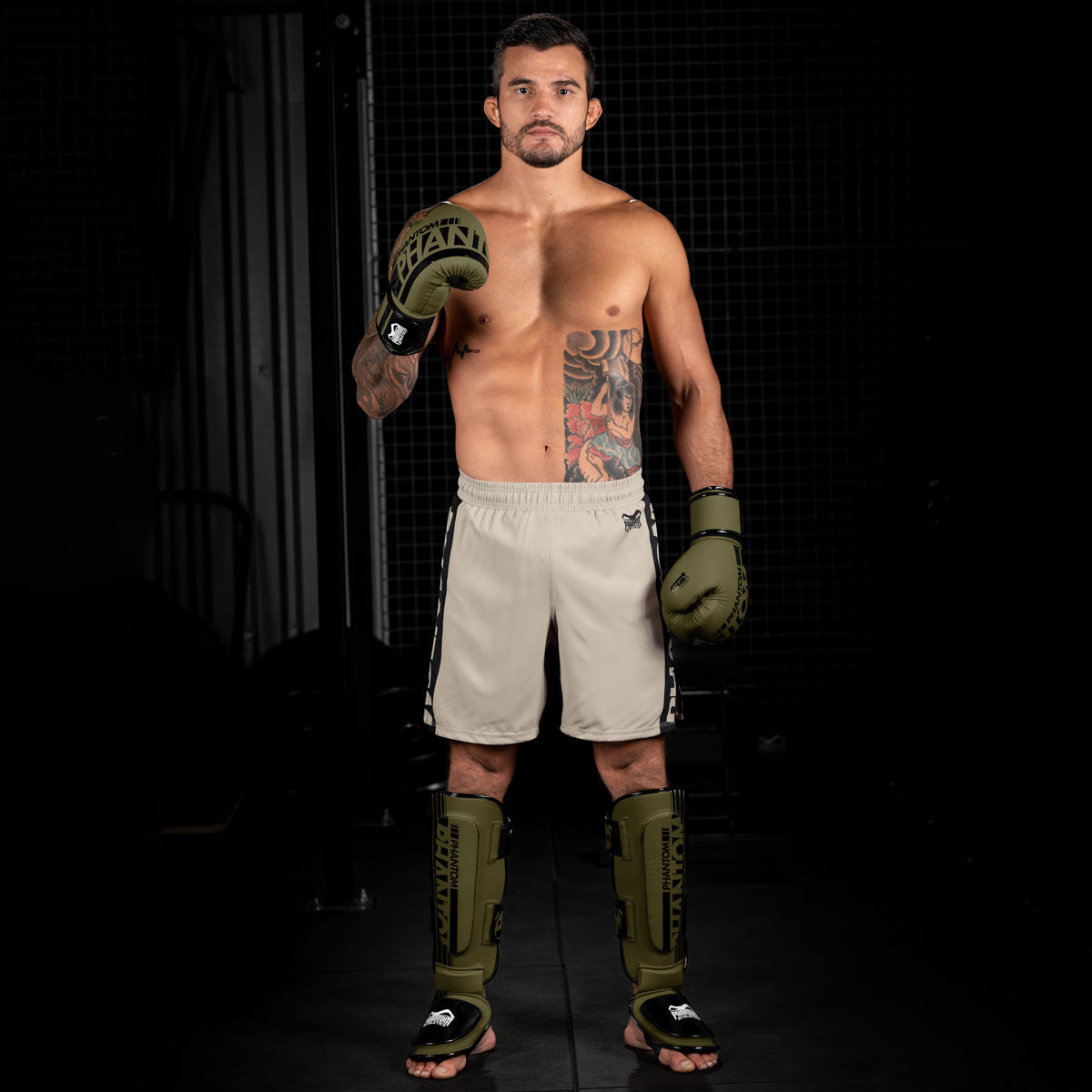 MMA Fighter im Gym mit der Army grünen Apex Fight Collection bestehend aus Boxhandschuhen, Hybrid Schienbeinschonern und Apex MMA Fightshorts.
