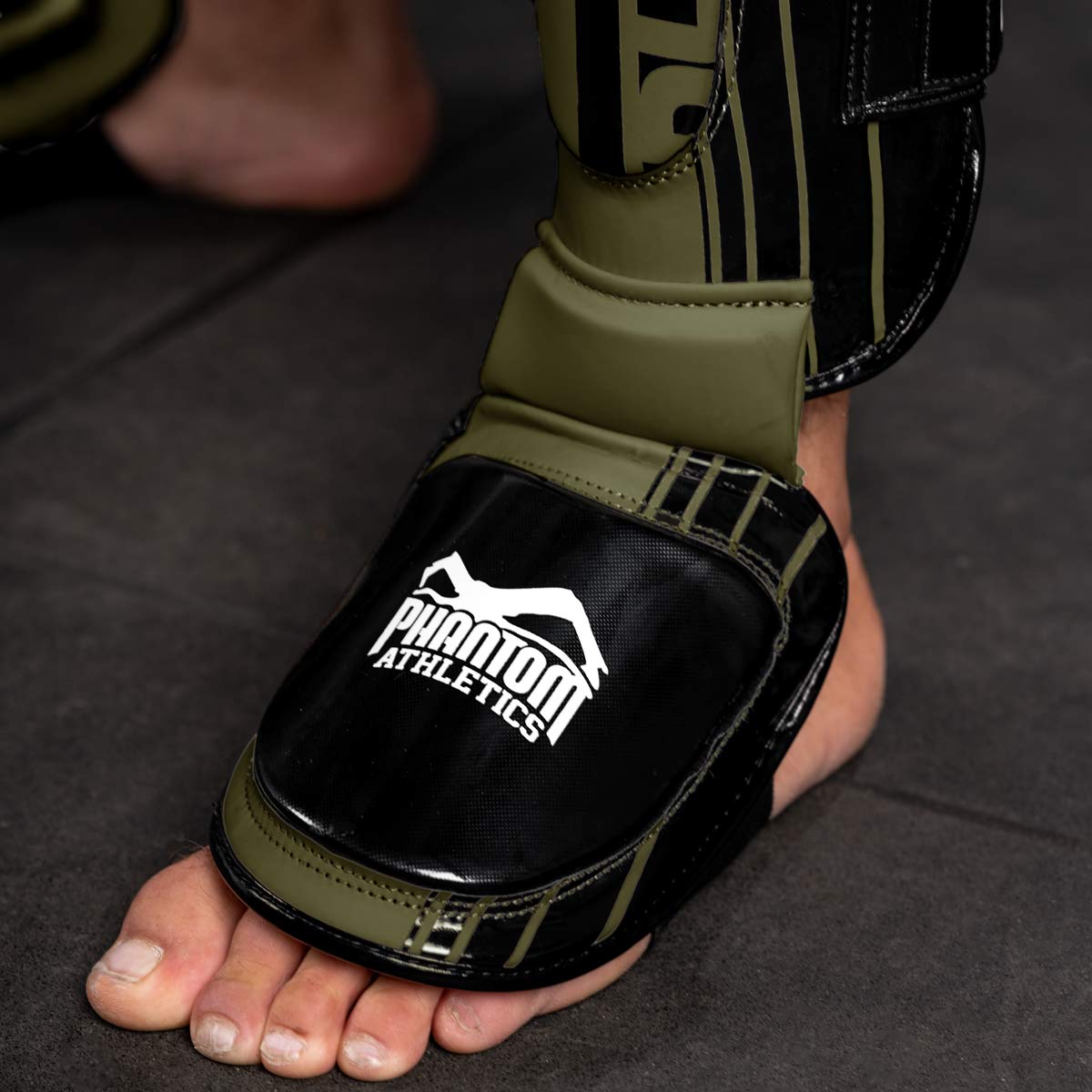 Die Phantom Apex MMA Schienbeinschoner in Armygrün im Detail mit dicken Vorderfußpolster im Gym.
