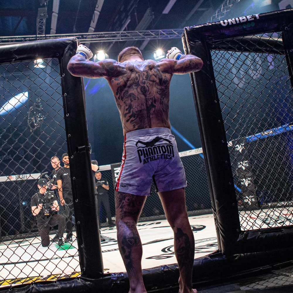 Die Phantom FLEX Fightshorts zählen zu den besten Fightshorts am Markt. Ultraleicht, mega flexibel und reißfest. Reduziert auf ein absolutes Minimum bietet sie dir maximale Performance in deinem Kampfsport. Egal ob BJJ, MMA, Muay Thai oder Kickboxen. Die FLEX Shorts von Phantom Athletics holen das beste aus dir raus. Hier im neuen VIRUS Look in weiß/rot/schwarz und großem Phantom Athletics Schriftzug auf der Seite.  UFC MMA Fighter Aleks Rakic beim Training.