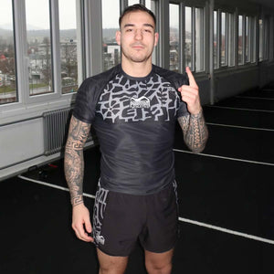 Phantom Athletics Groundgame Rashguard – ein eng anliegendes Compression-Shirt, das optimale Bewegungsfreiheit beim Bodenkampf wie Nogi-BJJ, Grappling oder Jiu-Jitsu bietet. Das atmungsaktive Material mit 4-Wege-Stretch und Sublimationsdruck schützt vor Reibung und Schürfwunden, während die Temperaturregulierung auch bei intensiven Runden für trockenen Komfort sorgt.