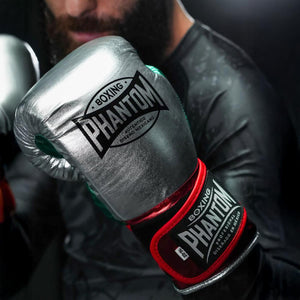 Stylische Phantom Athletics Boxhandschuhe Mexico in edlem Silber mit auffälligen Farbdetails, ideal für tägliche Kampfsport‑Workouts, Fitnessboxen und Sparring. Das robuste PU‑Kunstleder ist langlebig und vegan, während der schlanke Schnitt maximale Kontrolle bei jedem Punch ermöglicht. Ein Premium‑Produkt für ambitionierte Athleten.