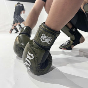 Die Muay Thai Boxhandschuhe in Army-Optik von Phantom Athletics stehen für Stärke, Disziplin und Funktionalität. Mit ihrer stoßabsorbierenden Polsterung und dem sicheren Klettverschluss sind sie perfekt geeignet für Sparring, Technik- und Padtraining im Muay Thai und Kickboxen.
