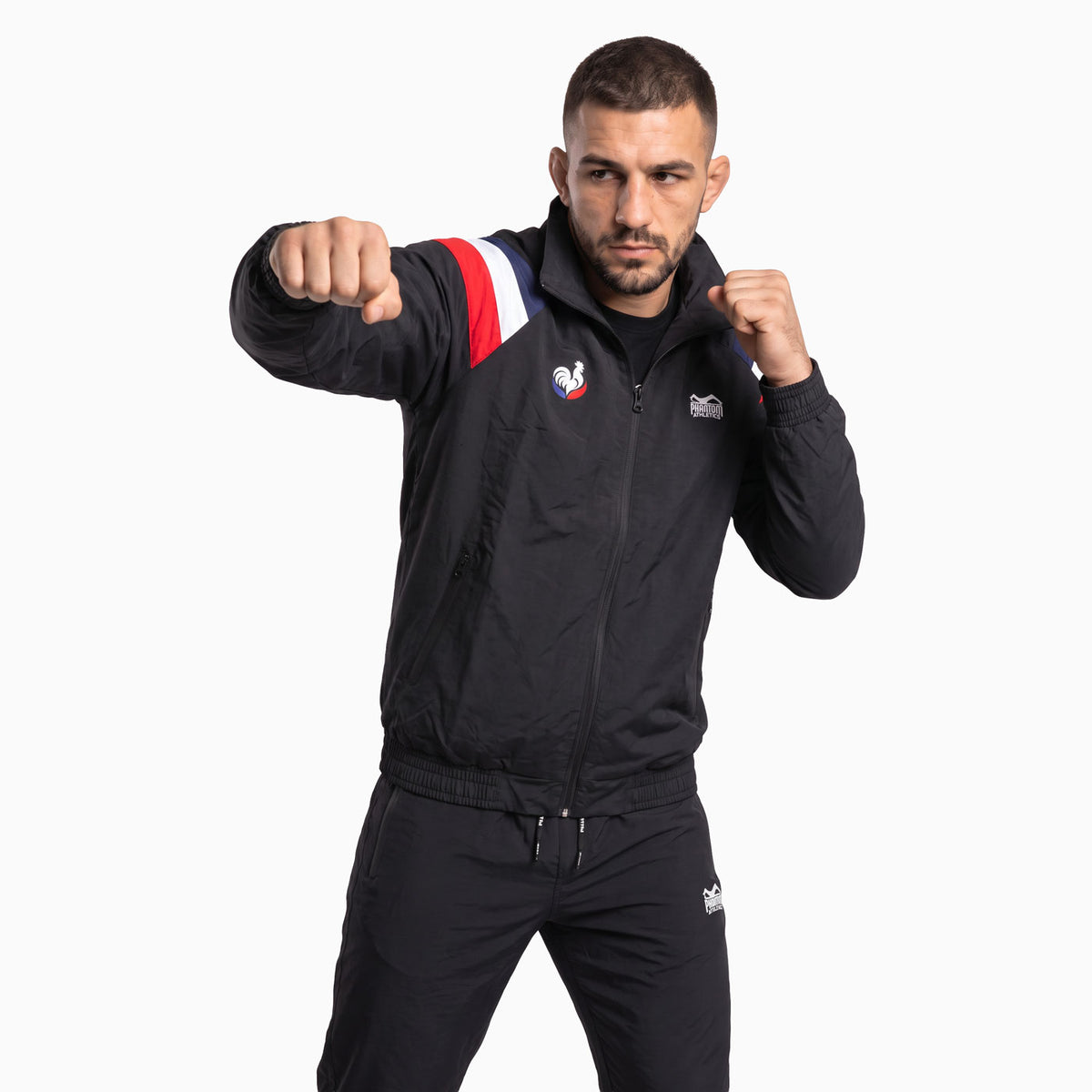 Die Phantom Athletics Trainingsjacke DMC Team France kombiniert schwarzen Retro-Style mit markanten Team-France-Akzenten. Das leichte, atmungsaktive Performance-Material bietet volle Bewegungsfreiheit für MMA, Boxen, Muay Thai, Fitness und Warm-up.