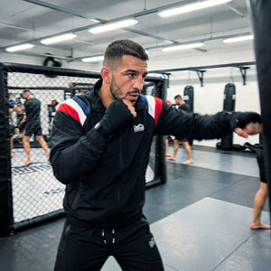 Die schwarze Phantom Athletics DMC Team France Trainingsjacke verfügt über ein atmungsaktives Mesh-Innenfutter, elastische Bündchen und verklebte Reißverschlüsse. Reflektierende Details und der lockere Schnitt sorgen für Funktion und Komfort beim Training und im Alltag.