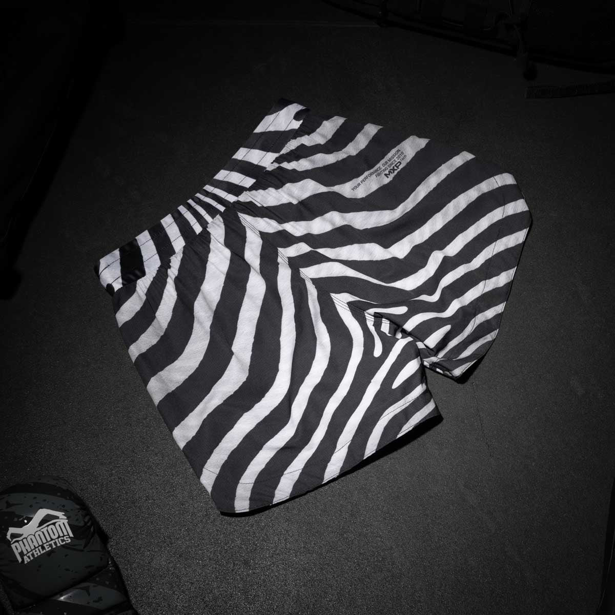 Phantom Athletics bringt mit den Fightshorts Fusion Zebra MMA Shorts auf den Markt, die sowohl optisch als auch technisch überzeugen. Der ergonomische Schnitt sorgt für Bewegungsfreiheit bei Takedowns und High Kicks, während das robuste Material auch härtesten Belastungen standhält.