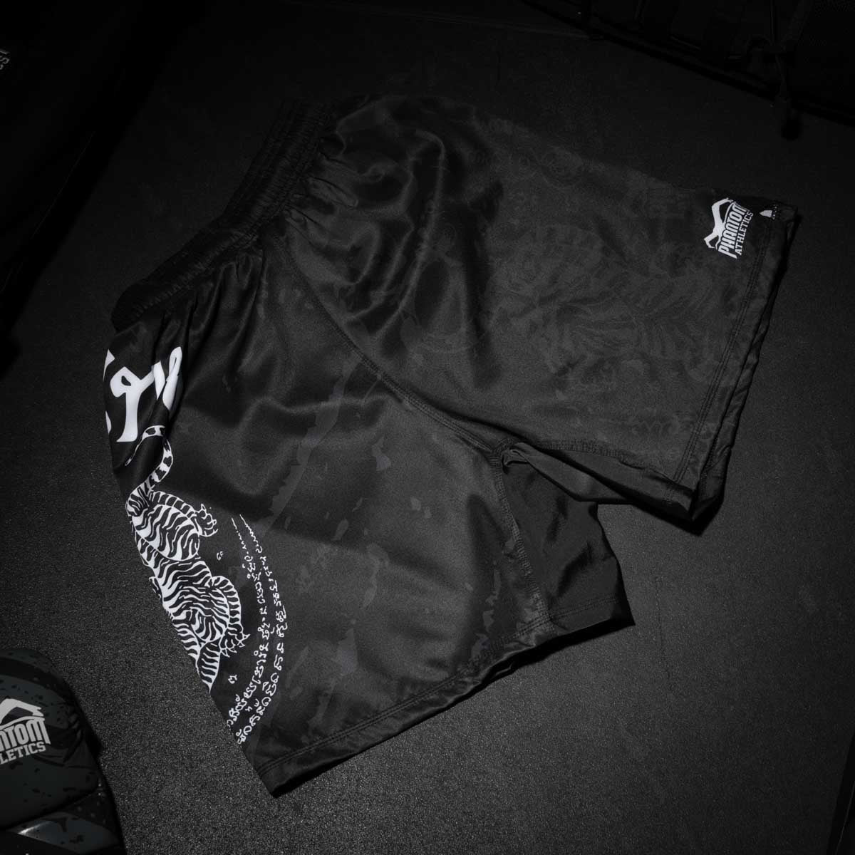 Mit den EVO Fightshorts Sak Yant bringt Phantom Athletics Muay Thai Kultur direkt in dein Kampfsporttraining. Das atmungsaktive Material, der kurze Schnitt und die elastischen Seitenschlitze sorgen für volle Flexibilität bei Kicks, Knietechniken und schnellen Kombinationen – ideal für Muay Thai, K1 und Kickboxen.