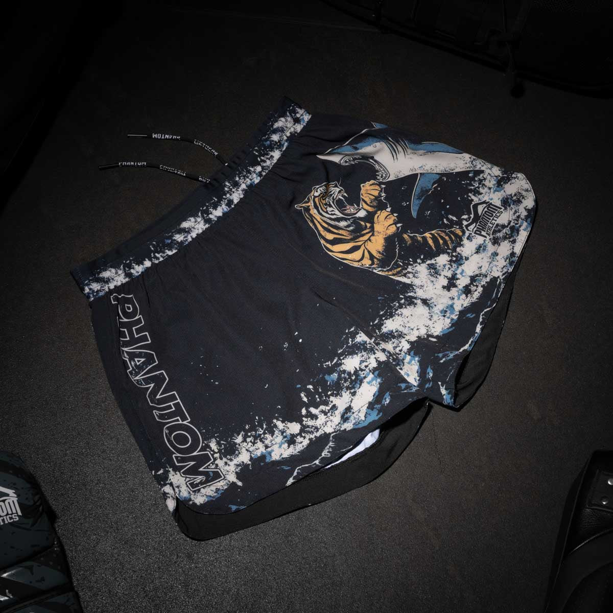 Phantom Athletics Fightshorts Fusion-R mit auffälligem Tiger-vs-Shark-Design – ein echter Blickfang für MMA, BJJ und No-Gi Training. Hochwertige Verarbeitung und sportlicher Schnitt machen diese Shorts zur idealen Wahl für anspruchsvolle Kampfsportler.