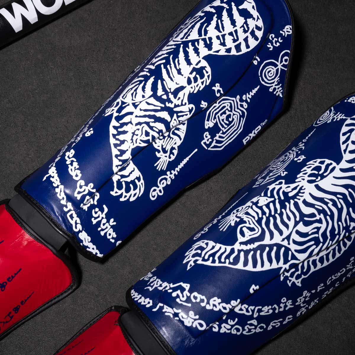 Phantom Muay Thai Schienbeinschutz für Thaiboxen und MMA Sparring, Wettkampf und Training. Im traditionellen Sak Yant Design und der Farbe Blau/Rot.