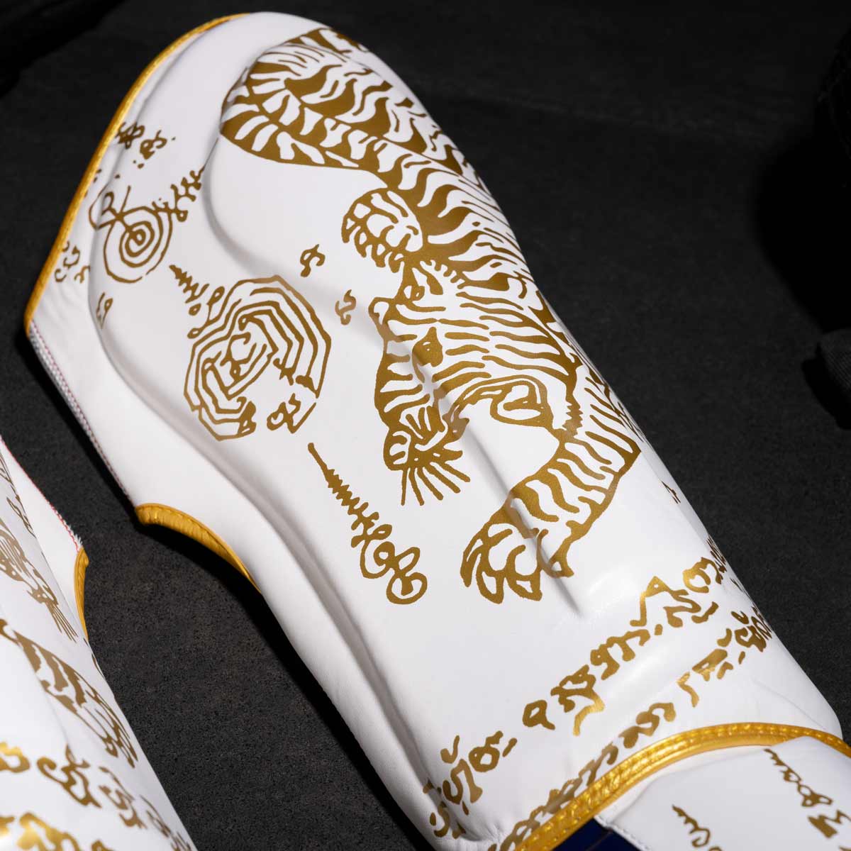 Phantom Muay Thai Schienbeinschutz für Thaiboxen und MMA Sparring, Wettkampf und Training. Im traditionellen Sak Yant Design und der limitierten Farbe Weiß/Gold.