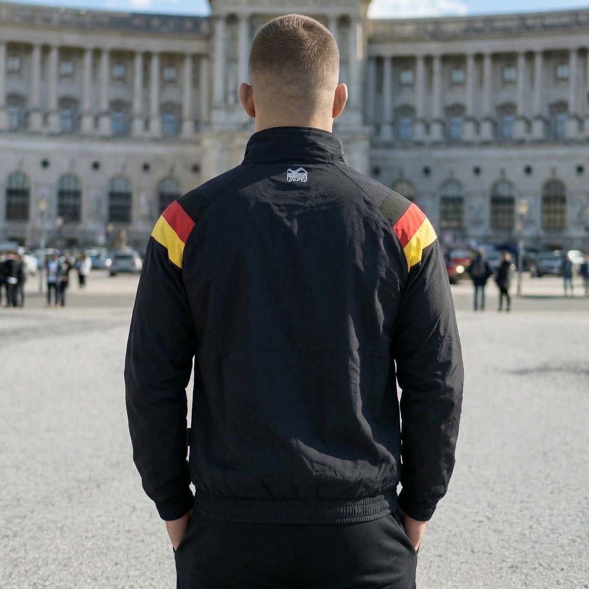 Die Phantom Athletics Trackjacket DMC Team Germany kombiniert klassischen Retro-Style in Schwarz/Rot/Gold mit moderner Performance für intensives Kampfsport-Training wie MMA, Boxen und Kickboxen. Das leichte, atmungsaktive Material mit Mesh-Innenfutter sorgt für optimalen Komfort und maximale Bewegungsfreiheit beim Warm-up und Sparring.