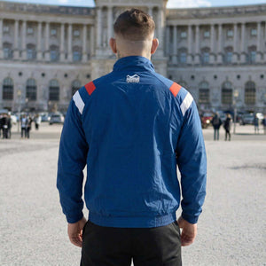 Die Phantom Athletics Track Jacket DMC Team Serbia in Blau kombiniert klassischen Retro-Style mit moderner Performance für intensives Kampfsport-Training wie MMA, Boxen und Muay Thai. Das leichte, atmungsaktive Material mit Mesh-Innenfutter sorgt für optimalen Komfort und maximale Bewegungsfreiheit beim Warm-up und Sparring.
