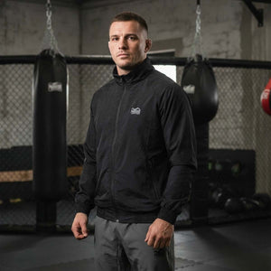 Hochwertige Phantom Athletics Track Jacket DMC in klassischem Schwarz mit sportlicher Passform, ideal für Warm‑ups, Technik‑Drills oder Cool‑Downs im MMA, Boxen und Kickboxen mit atmungsaktivem, leichtem Material für optimalen Komfort. Die funktionelle Jacke unterstützt Bewegungsfreiheit bei jedem Training und zeigt die Premium‑Qualität der Marke.