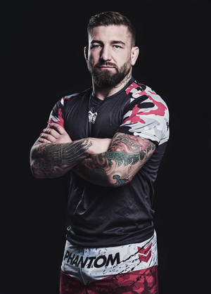 MMA Fighter Dominic Schober. Das Trainingsshirt EVO Camo Rot ist ideal für MMA, Muay Thai und Fitnesstraining und bietet Flexibilität und Komfort bei allen Bewegungen. Das atmungsaktive Gewebe sorgt für ein angenehmes Tragegefühl und hält die Haut trocken. Das auffällige rote Camo-Muster macht das Shirt zu einem sportlichen Blickfang.