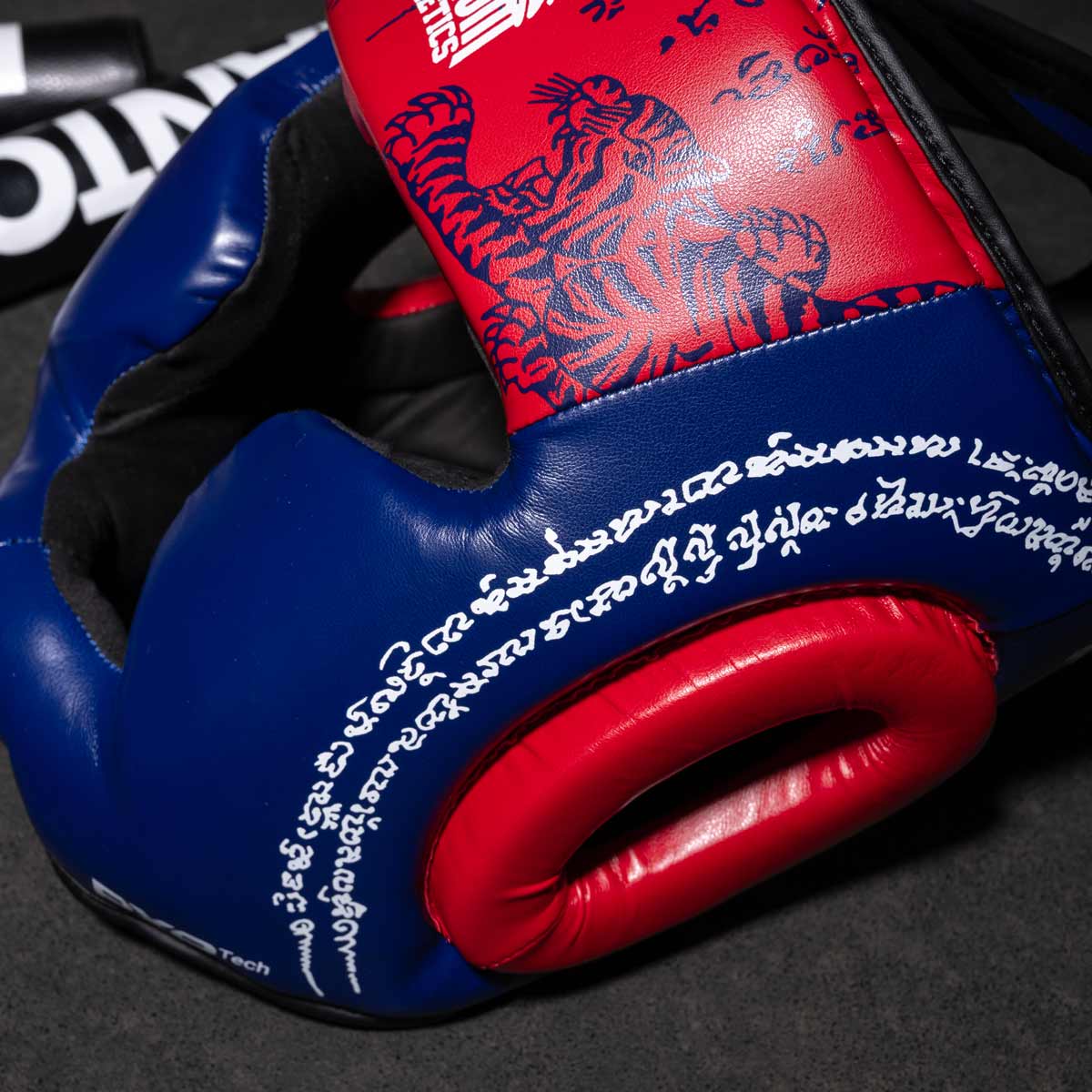 Phantom Muay Thai Kopfschutz für Thaiboxen und MMA Sparring, Wettkampf und Training. Im traditionellen Sak Yant Design und der Farbe Blau/Rot.
