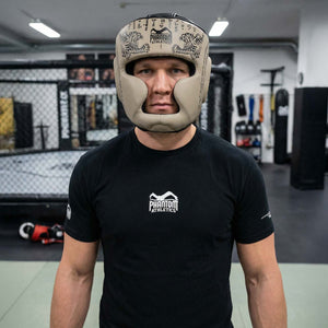 Robuster Phantom Athletics Muay Thai Headguard in Sand‑Beige, entwickelt für intensives Sparring und technikorientiertes Training im Thaiboxen, Kickboxen und MMA mit umfassendem Schutz für Stirn, Wangen und Kinn. Die dicke Polsterung absorbiert harte Treffer zuverlässig und sorgt für maximale Sicherheit im Gym. Ein Premium‑Kopfschutz für ambitionierte Kampfsportler.