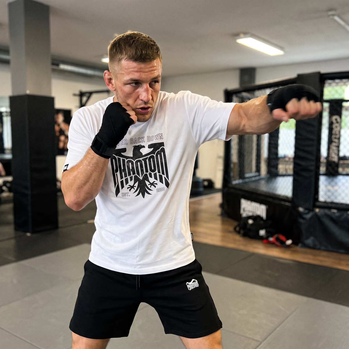 Das Phantom Athletics T-Shirt GERMANY NBD in Weiß verbindet einen kontrastreichen schwarzen Frontprint mit einer sportlichen Passform und hoher Bewegungsfreiheit. Die hochwertige Fightwear eignet sich für Boxen, Kickboxen, Muay Thai, MMA und Functional Fitness.