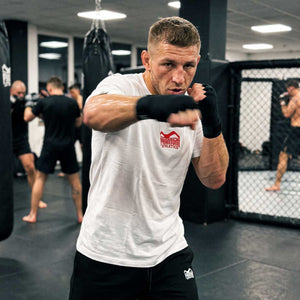 Das Phantom Athletics Team T-Shirt in Weiß verbindet einen cleanen Look mit einem markanten roten Logo und dezentem Branding im Nacken. Die hochwertige Fightwear ist ideal für Kampfsport, Functional Fitness, Gym und Freizeit.