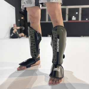 Die Apex Striking Schienbeinschoner im Army-Design von Phantom Athletics bieten dir zuverlässigen Schutz bei harten Kicks im Muay Thai und Kickboxen. Dank ihrer anatomischen Passform und starken Polsterung eignen sie sich perfekt für intensives Sparring und Techniktraining.