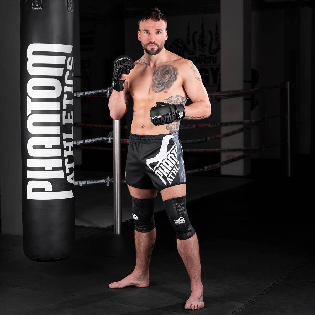 MMA Fighter mit Phantom APEX Grappling Knieschützern, Phantom Apex Sparringshandschuhen und dem Phantom High Performance Boxsack