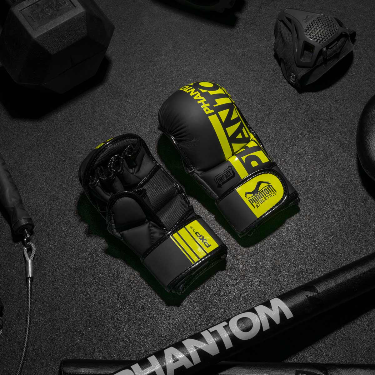 Die Phantom Apex MMA Sparringshandschuhe am Gymboden neben der Phantom Trainingsmaske.