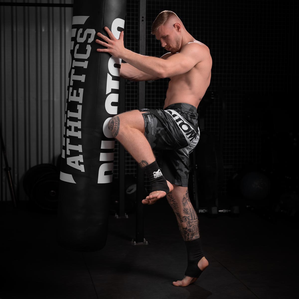 Kickboxer beim Sandsacktraining mit den Phantom Ankle Guards Knöchelschonern schlägt einen Kniestoß.