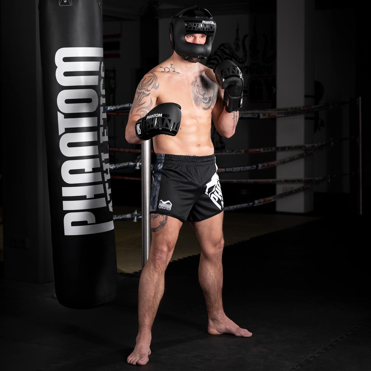 Thaiboxer mit dem Phantom Apex Facesaver Kopfschutz und den Phantom Apex Sparringshandschuhen im Muay Thai Gym beim Training