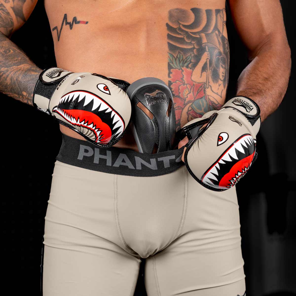 MMA Profi steckt den Phantom Tiefschutz in seine Fightshorts und trägt dabei die Phantom Fight Squad MMA Handschuhe in Sand