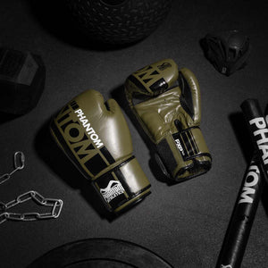 Die army grünen Phantom APEX Boxhandschuhe auf dem Gymboden mit der Phantom Trainingsmaske