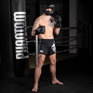 Thaiboxer mit dem Phantom Apex Facesaver Kopfschutz und den Phantom Apex Sparringshandschuhen im Muay Thai Gym beim Training