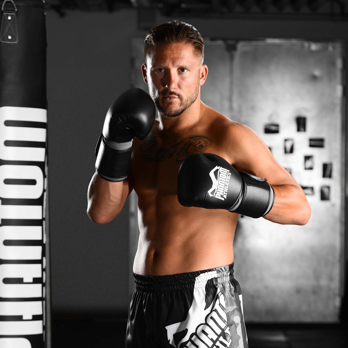 Kickbox Legende Andy Souwer mit den Phantom Elite ATF Boxhandschuhen im Gym neben einem Phantom Sandsack.