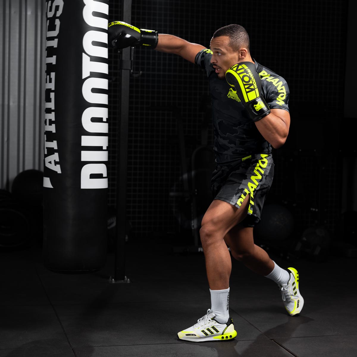 Die Phantom EVO Fightshorts sind die idealen Shorts für deinen Kampfsport. Ganz egal ob MMA, BJJ, Kickboxen oder Muay Thai. Durch das ultraleichte, elastische, reissfeste und schnelltrocknende Material bieten sie die volle Bewegungsfreiheit und maximalen Komfort, so dass du dich ganz auf deinen Fight oder dein Training konzentrieren kannst. Hier in der Farbe Neon Camo. MMA Fighter beim Training am Sandsack.